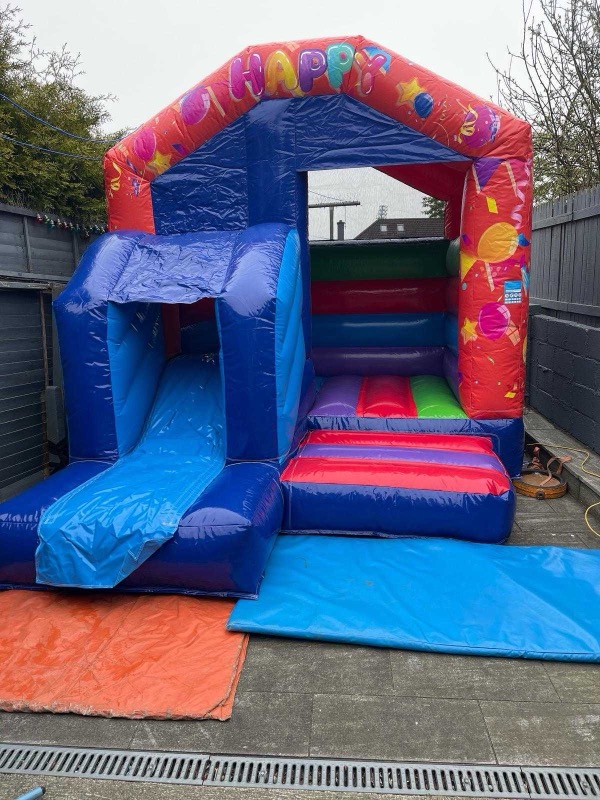 Red 'Happy Birthday' bouncy castle with slide for parties in Cork