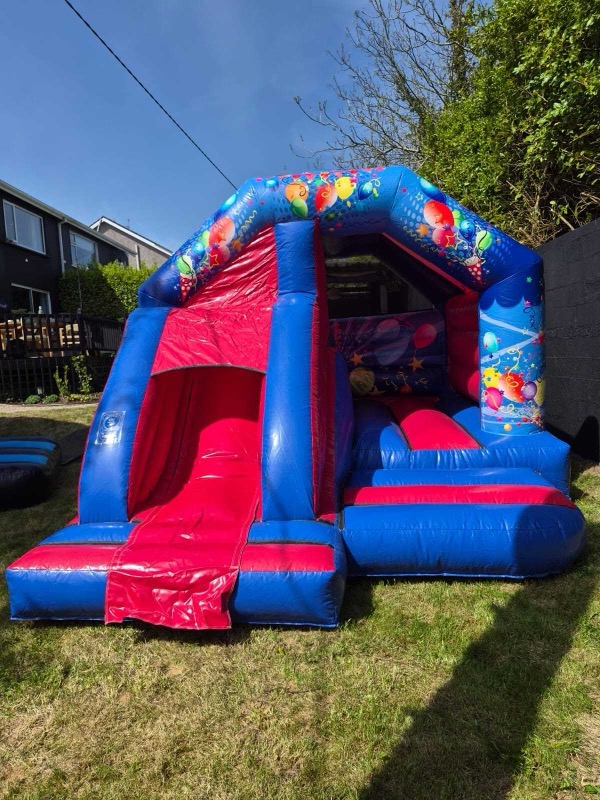 Blue and red bouncy castle with slide and balloon design for parties in Cork