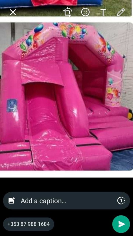 Pink bouncy castle with balloon design and slide for parties in Cork