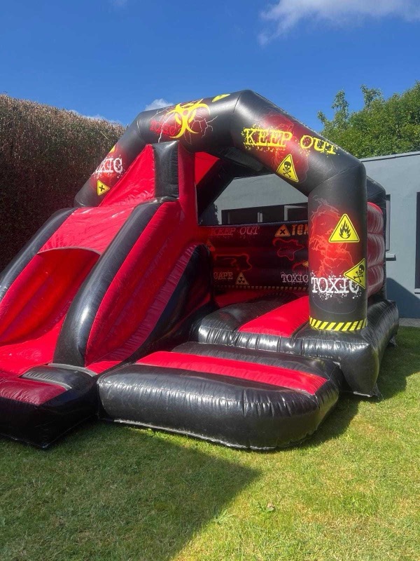 Black and red Toxic-themed bouncy castle with slide for parties in Cork