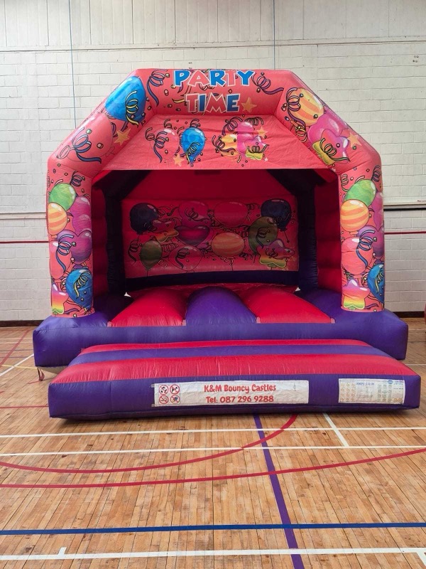 Red 'Party Time' bouncy castle with balloon design for parties in Cork